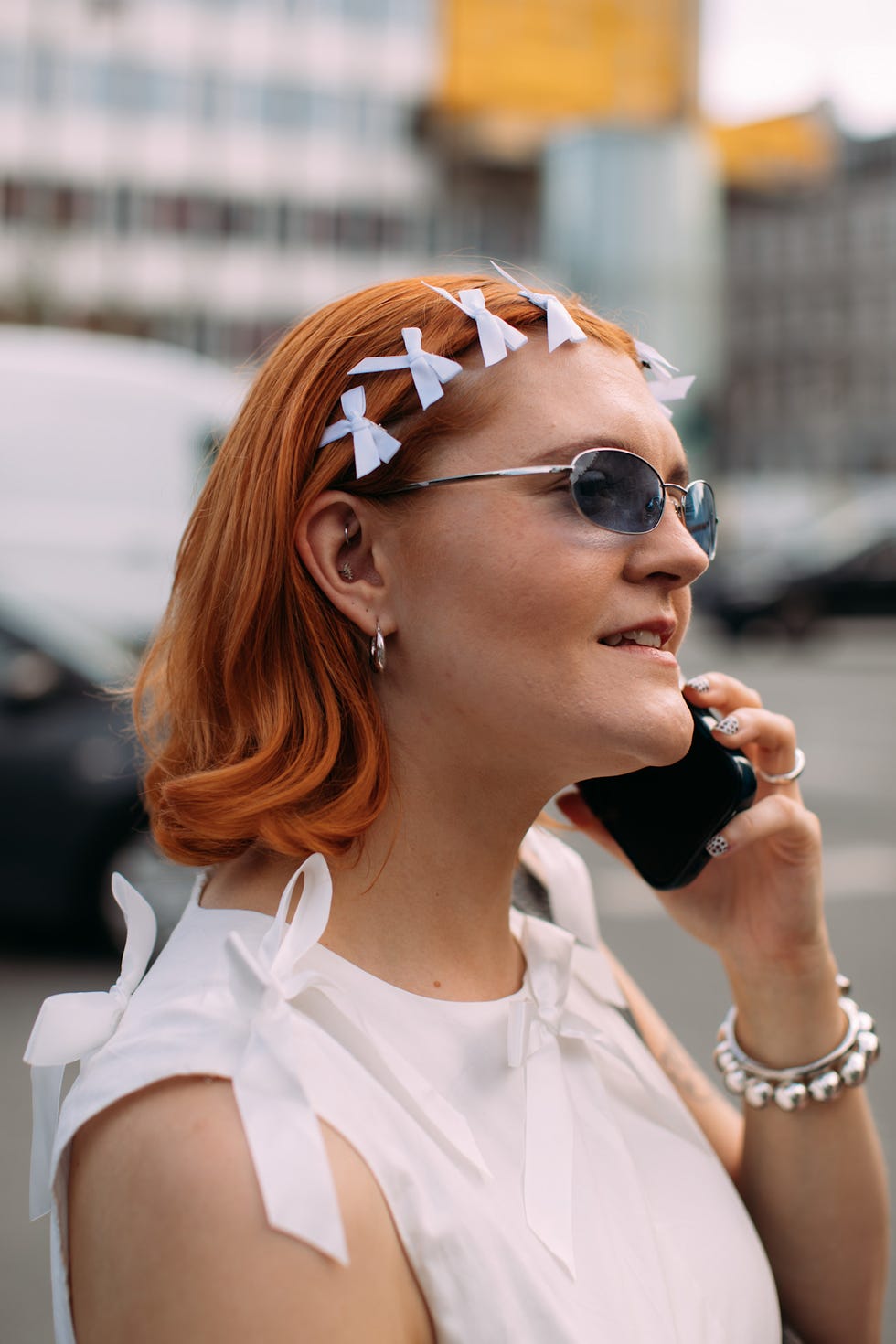 redhead with bob haircut talking on a smartphone wearing a stylish outfit with hair accessories bob haircuts at copenhagen fashion week