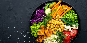 bowl dish with brown rice, cucumber, tomato, green peas, red cabbage, chickpea, fresh lettuce salad and cashew nuts healthy balanced eating