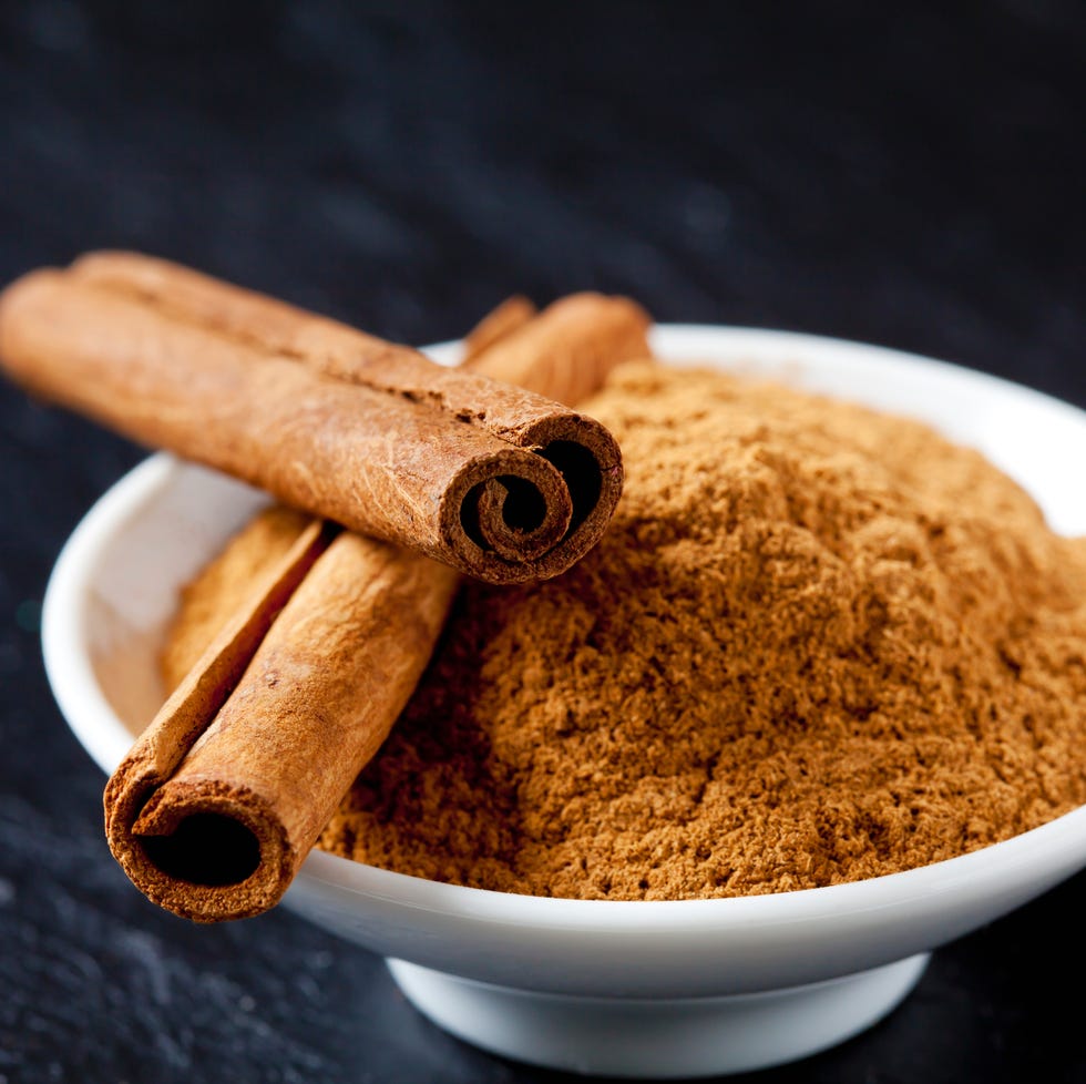 Bowl of cinnamon powder and two cinnamon sticks bowl of cinnamon powder and two cinnamon sticks