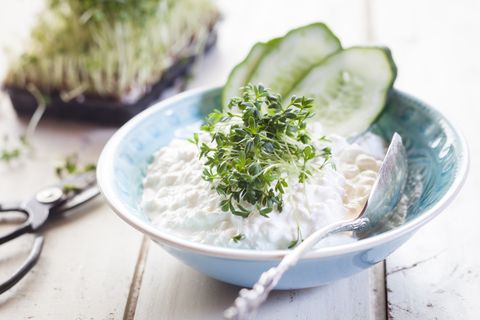 Bowl of cottage cheese with cress and cucumber slices