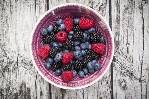 bowl of different wild berries on wood