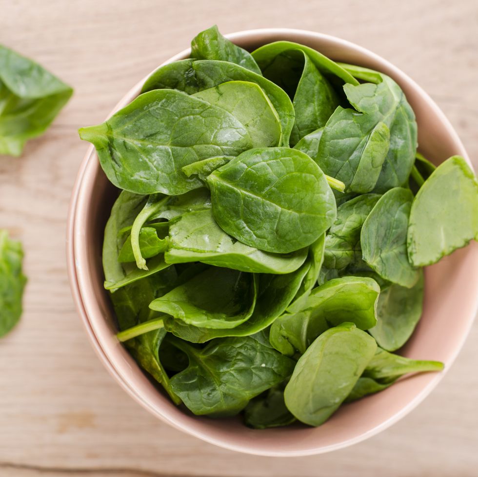 bowl of fresh spinach leaves on wood