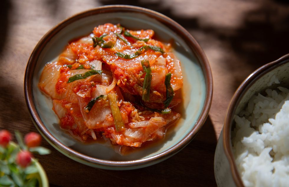 a bowl of kimchi and a bowl of rice on the rustic table