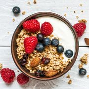 bowl of oat granola with yogurt, fresh raspberries, blueberries