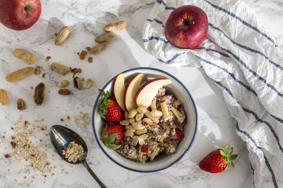 bowl of oats porridge topped with fruit and nuts