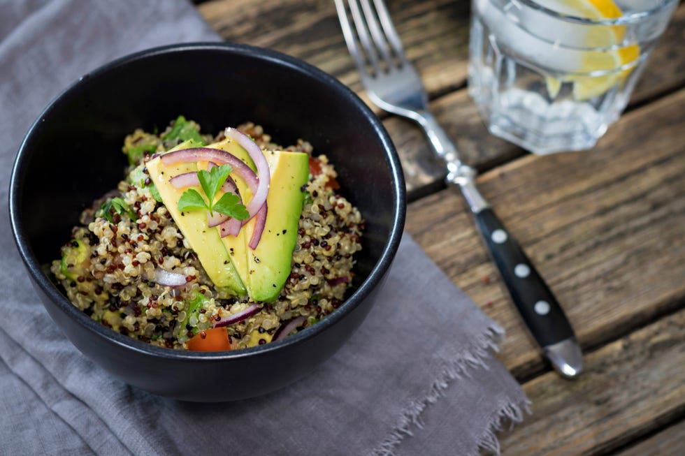 bowl of quinoa tricolore with avocado, red onion, tomatoes and flat leaf parsley
