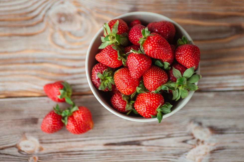 bowl of ripe strawberries on wooden table stock photo