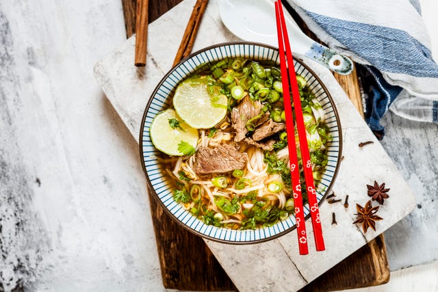 Bowl of Vietnamese Pho with rice noodles, mung beans, cilantro, spring onions and limes