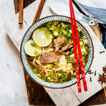 Bowl of Vietnamese Pho with rice noodles, mung beans, cilantro, spring onions and limes