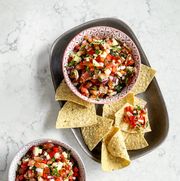 bowls of salsa with corn chips on white marble background