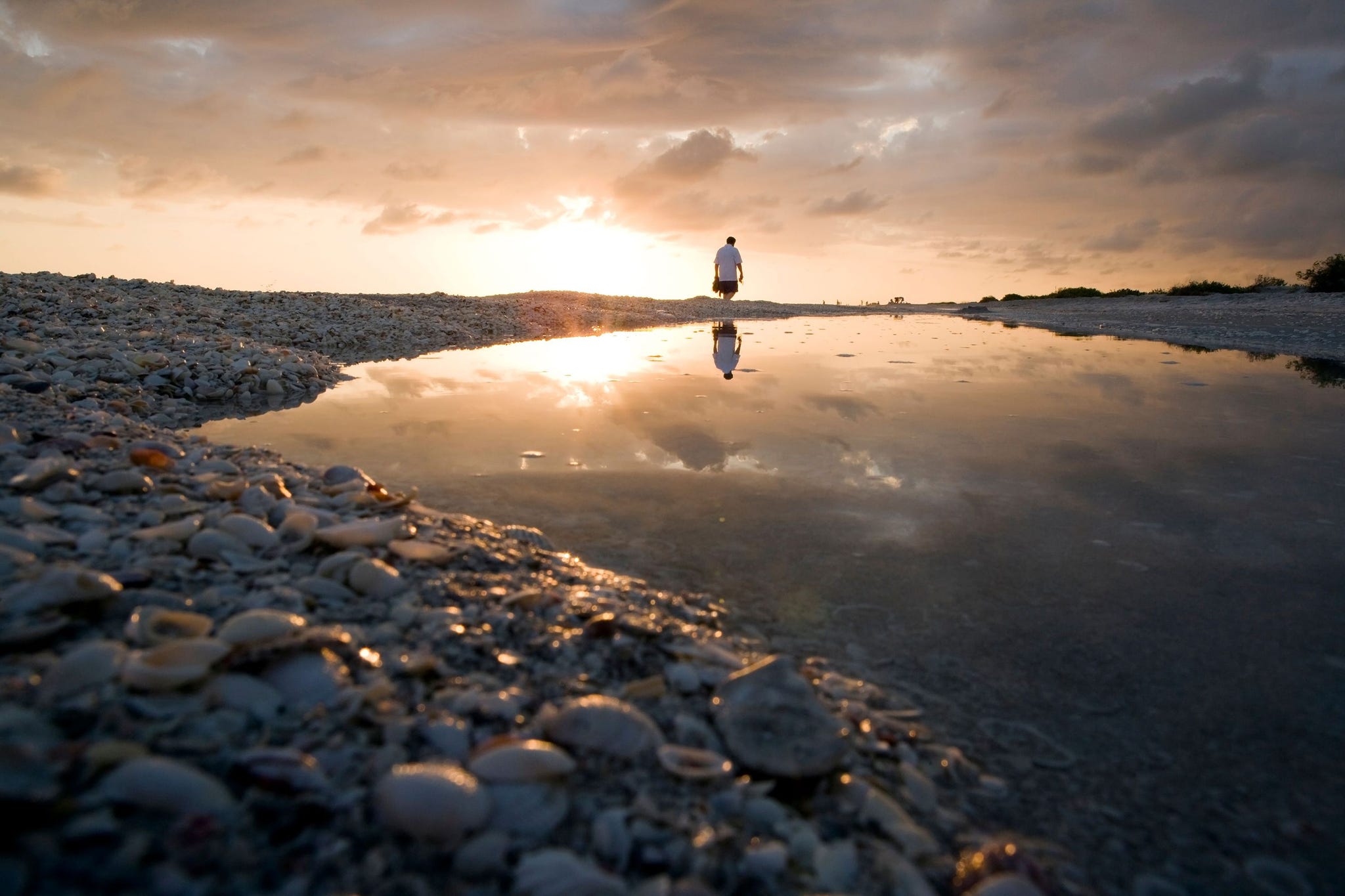 Een bezoeker loopt bij zonsondergang langs Bowmans Beach op Sanibel Island Florida