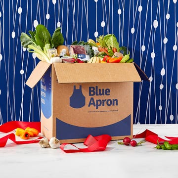 cardboard box filled with fresh ingredients and a ribbon showcasing a meal kit service