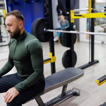 male athlete sitting and resting after lifting weight on bench press in the gym