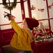 boy making a plane fly in front of a christmas toy store