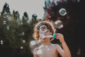 niño haciendo pompas en jardín