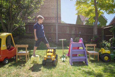 boy walking on toys arranged in yard
