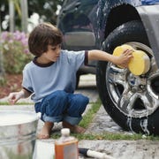 Boy (5-7) washing car wheel with sponge boy washing car wheel with sponge