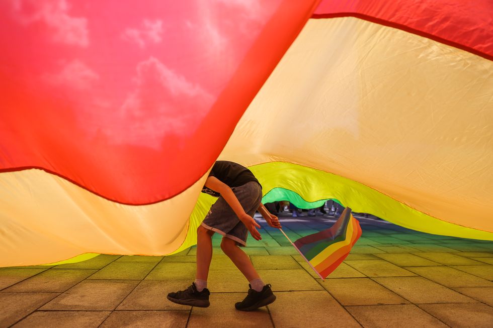 a child running under a large rainbow flag