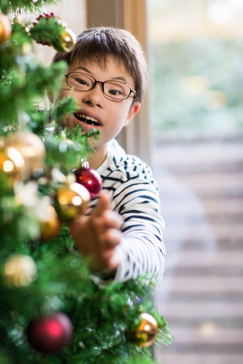 a boy with downs syndrome hanging decorations on a christmas tree