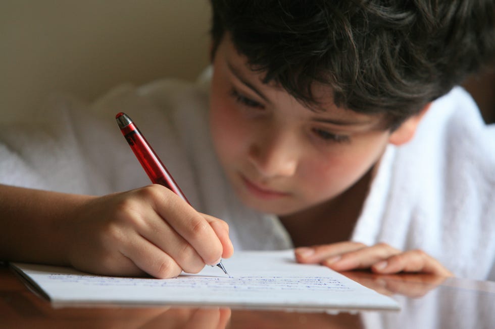 niño pequeño escribiendo en un papel reciclaje