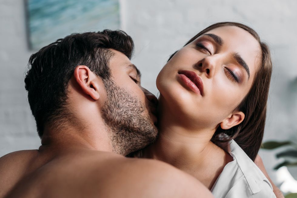 boyfriend kissing sensual girlfriends neck in bedroom in morning