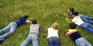 Children laying on grass picking dandelions,Santa Fe National Forest, NM