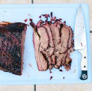 smoked brisket cut up on a cutting board with a knife