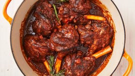 braised lamb shanks in a sauce with carrots and rosemary in a dutch oven