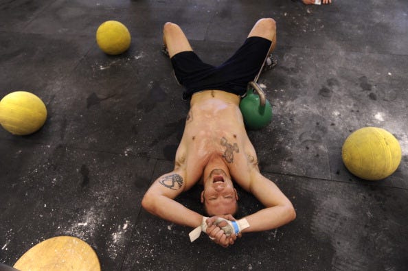 Brandon Deines, of Longmont, who trains with Coal Creek CrossFit, lays on the ground in exhuastion after finishing his workout challenge. This workout challenge included 500 yards on a row machine, 10 Burpees, 40 snatches with a 53 lbs kettle bell, and 30