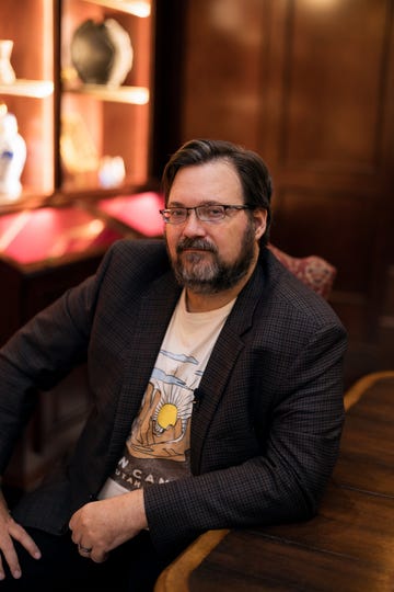 a person seated at a wooden table with a dark background