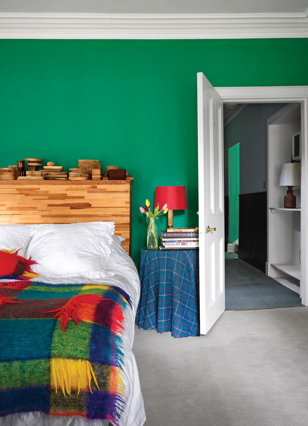Guest room with green wall and plaid throw on bed