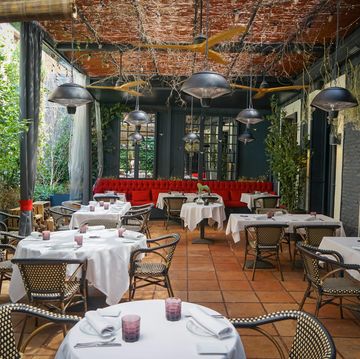 terraza con vegetacion mesas y un sillon rojo del restaurante lafayette