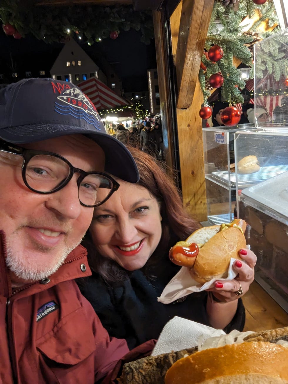 person holding a hot dog in a festive outdoor market