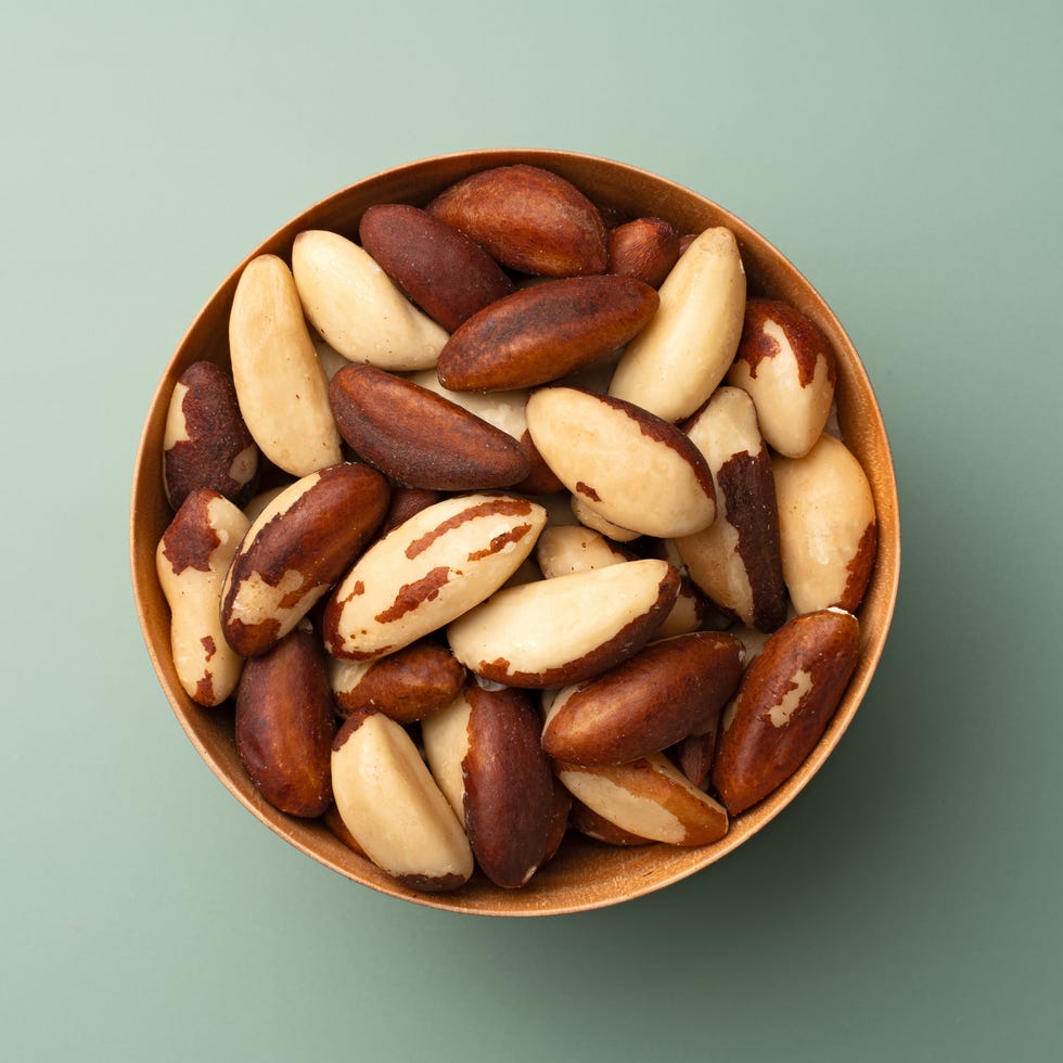 Brazil Nuts in Wooden Bowl on Green Background brazil nuts in wooden bowl on green background