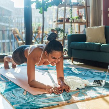 brazilian woman exercising at home in front of a laptop monitor