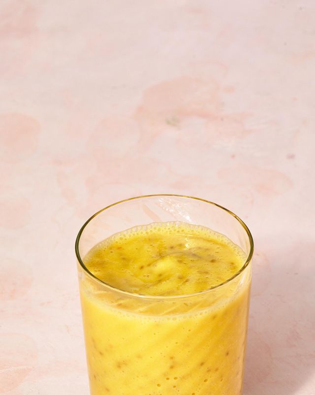 a glass with a bright yellow smoothie