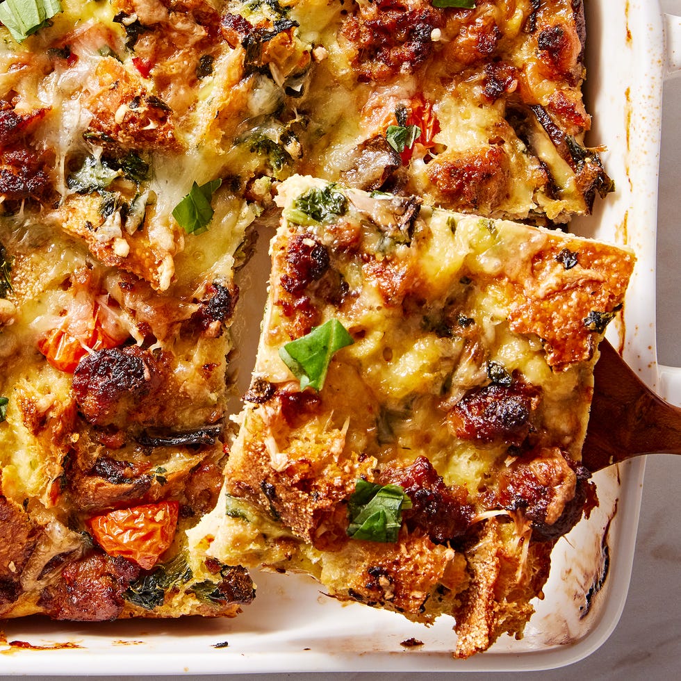 breakfast casserole in a white baking dish with italian sausage, mushrooms, tomatoes, and spinach