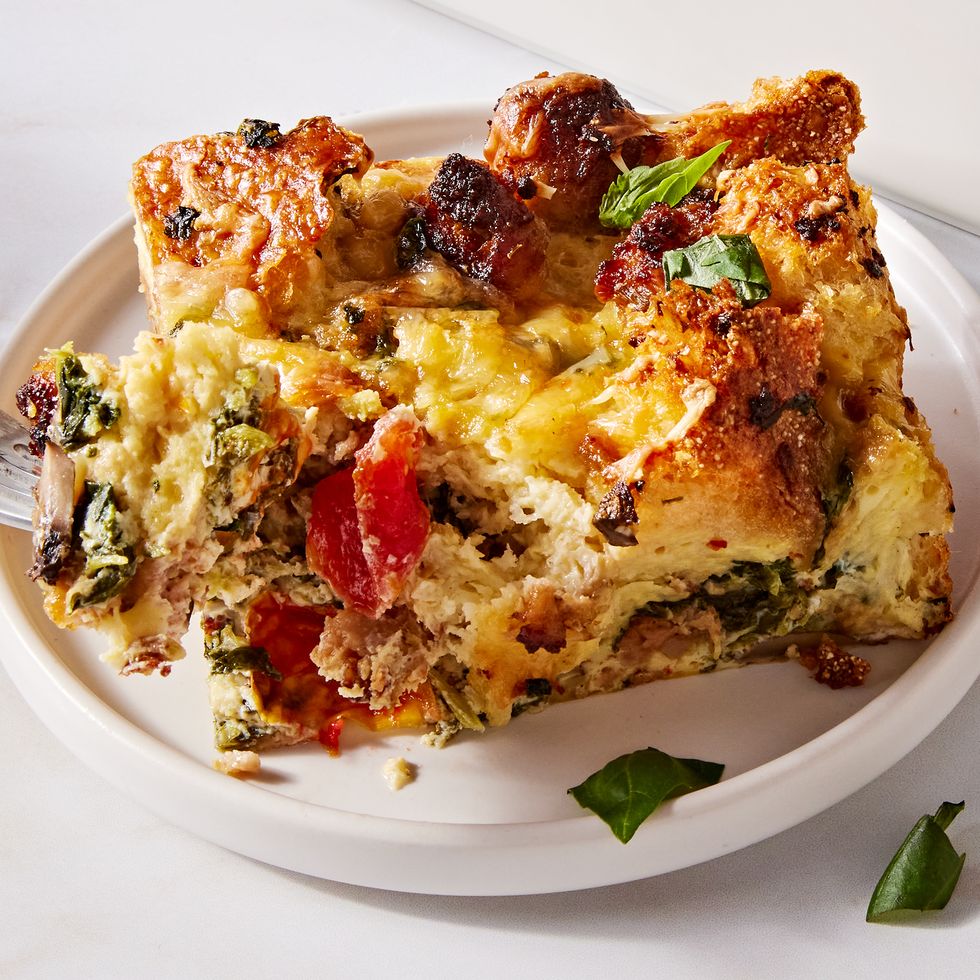 breakfast casserole in a white baking dish with italian sausage, mushrooms, tomatoes, and spinach