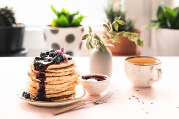 breakfast table with pancakes, blueberry jam and tea