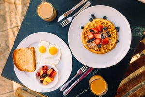 breakfast with sunny side up fried eggs, waffle and fruits