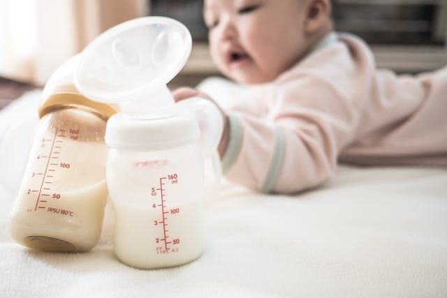 close up of milk bottles against baby girl on bed at home