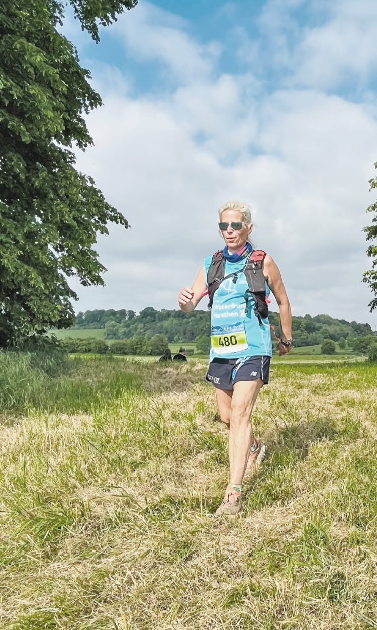 active woman wearing a hydration pack while run/walking in a rural environment