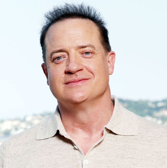 brendan fraser looking ahead for a photograph and smiling, he wears a cream colored polo shirt
