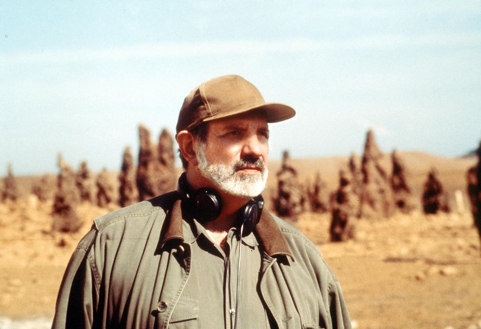 a man wearing a hat and a microphone in front of a desert