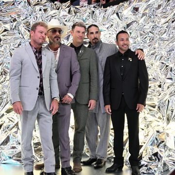 five men stand together and pose for photos while looking to the right, behind them is a silver background