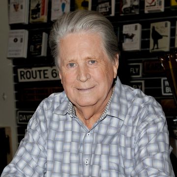a man in a patterned white and blue collared shirt smiles at the camera