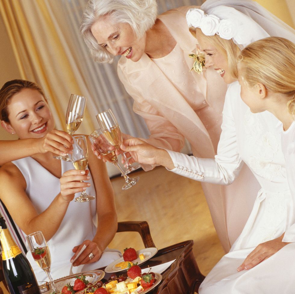 three women, bride and a young girl toasting with champagne