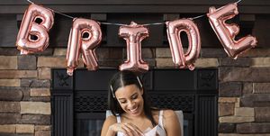 woman opening up gift at bridal shower under balloons that say bride