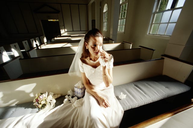 Bride crying, sitting on pew in empty church