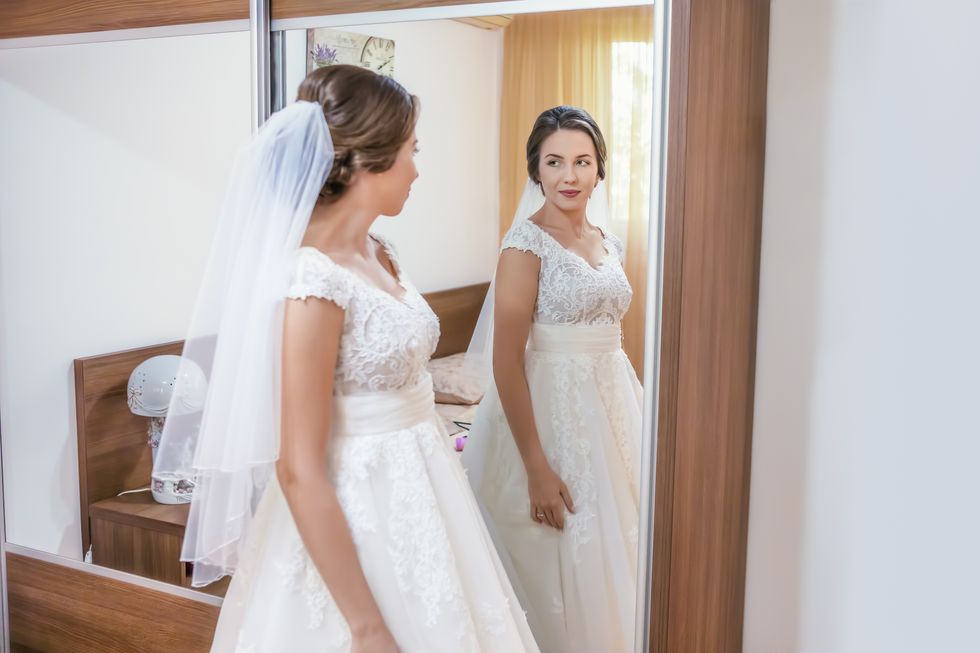 Bride in wedding dress looking in the mirror